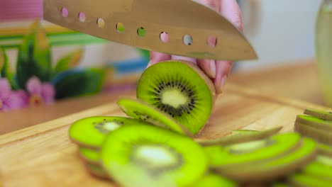 Women's-hands-Housewives-cut-with-a-knife-fresh-kiwi-on-the-cutting-Board-of-the-kitchen-table